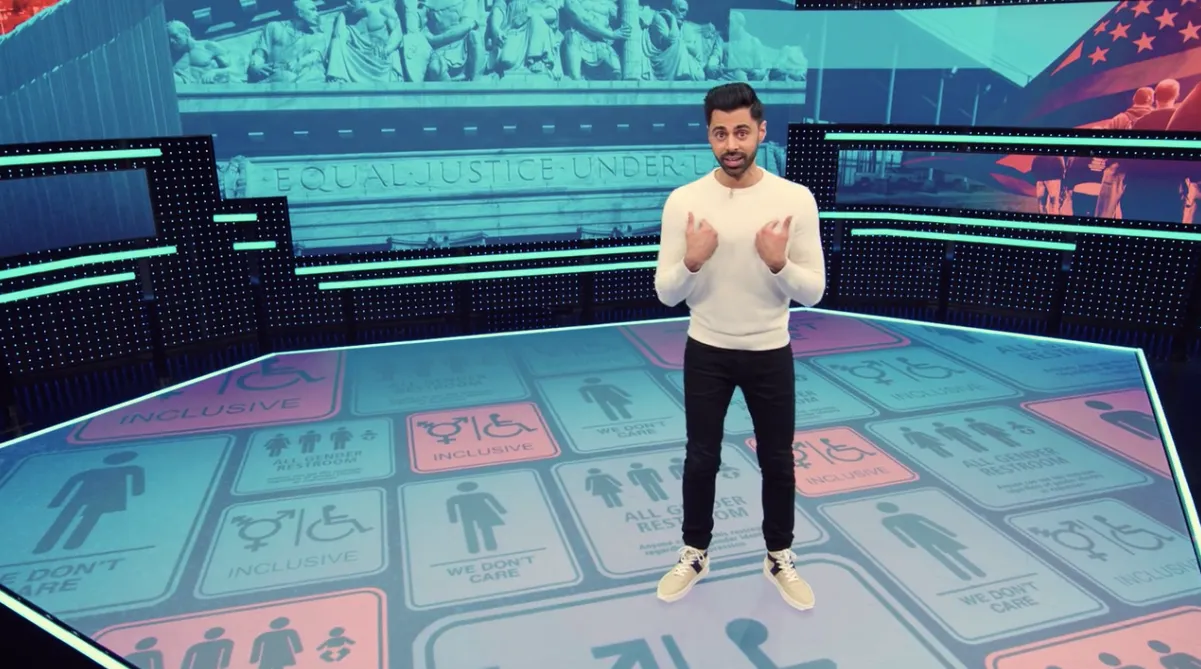 Hasan Minhaj on the set, graphics filling the LED walls behind him and the floor beneath him