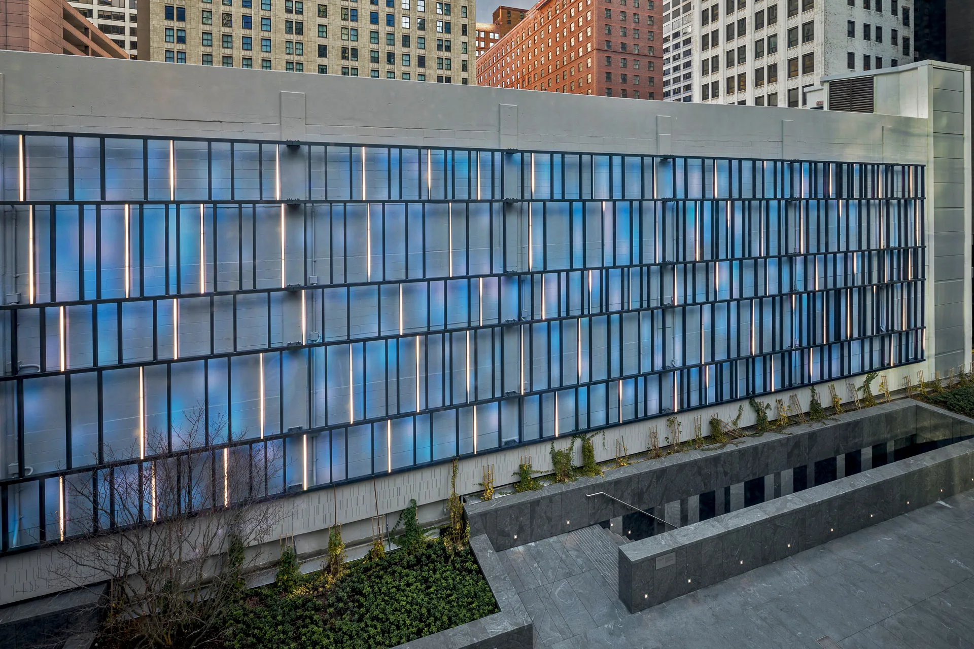 Sensing Change: the illuminated trellis against the concrete wall of the terrace, lit in blue and white